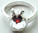 Bow-tie pattern design sterling silver ring holding a rounded red cz stone in middle
