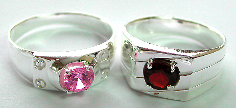 Thick band sterling silver ring with carved-in line pattern decor holding a rounded red garnet stone in middle 