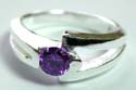 Sterling silver ring with rounded purple cz stone embedded at center and carved-out pattern on both sides