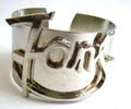 Fashion bangle in plain wide band design with the word 'Fans' pattern decor at center