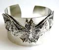 Fashion bangle in plain wide band design with flying bat pattern decor at center