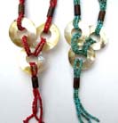 Three sea shell circle ornaments hanging from multi string beaded necklace