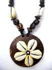 Flower design on wooden pendant hanging from seashell and wooden bead string 