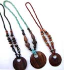 Wooden circular pendant dangling from a variety of shapes and size beaded necklace 