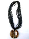 Exotic decor on wooden circle pendant hanging from multi black beaded necklace 