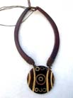 Handcrafted adornment on circular wooden pendant dangling from wood necklace 
