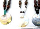 Oval sea shell pendant suspended from colored and wooden beaded necklace 