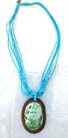 Coconut wood, oval pendant with aqua colored seashell in center hanging from multi string turquoise beaded necklace 