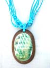 Coconut wood, oval pendant with aqua colored seashell in center hanging from multi string turquoise beaded necklace 