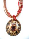 Oval shaped sea shell pendant suspended by brown cord necklace with red beads 
