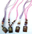 Rectangular wooden pendant with unique painted design on colored bead necklace with an assortment of beads at base